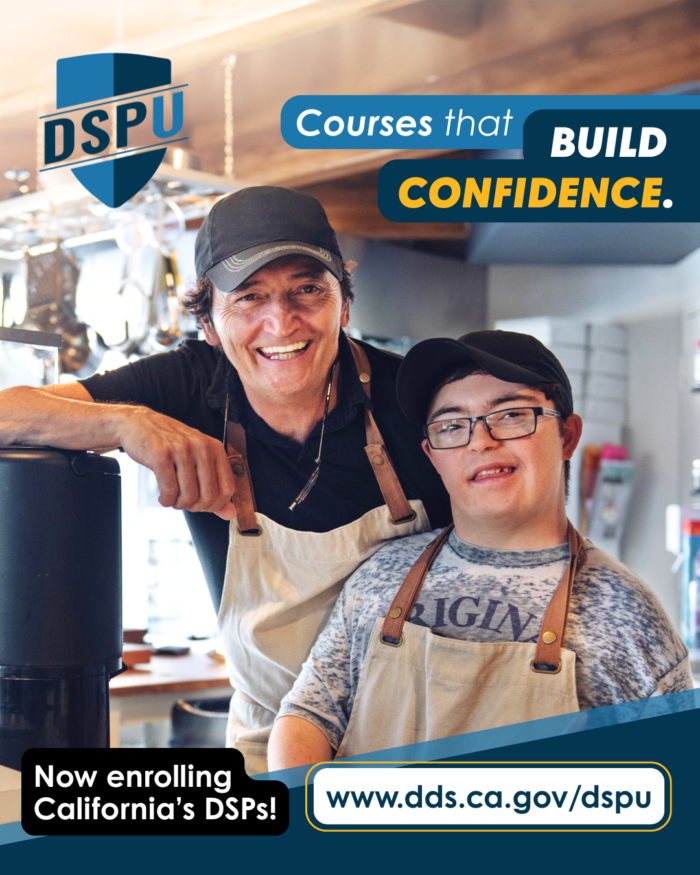 Two individuals, a direct support professional and a person with down syndrome, smile while working at a restaurant or coffee shop.